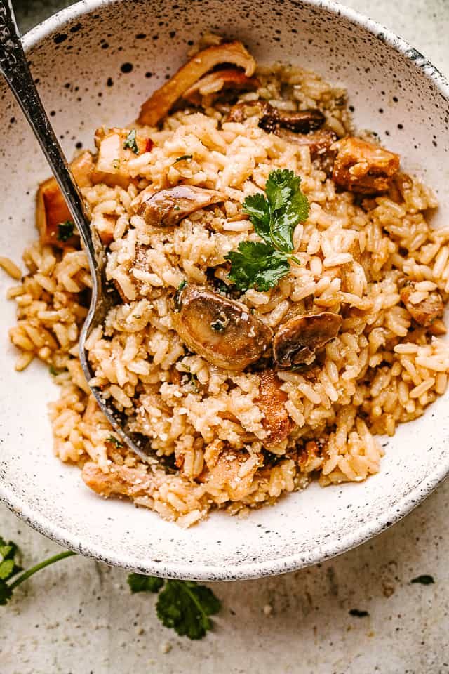 Completed chicken and mushrooms with rice, served in a white bowl and garnished with parsley