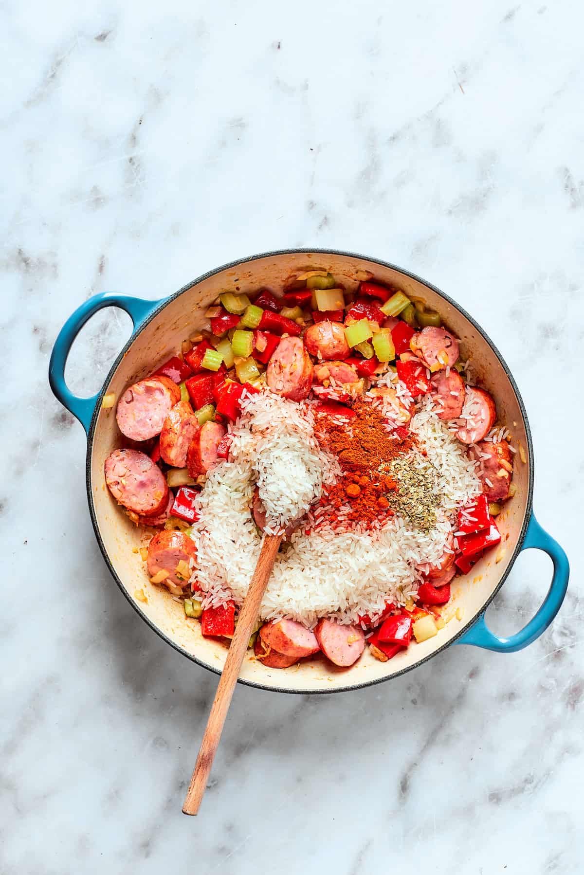Spices and rice are added to the pot of jambalaya.