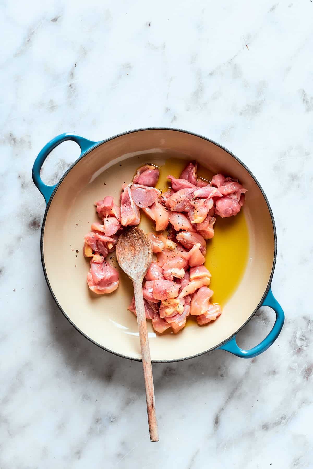 Chicken cooks in olive oil in a pot.