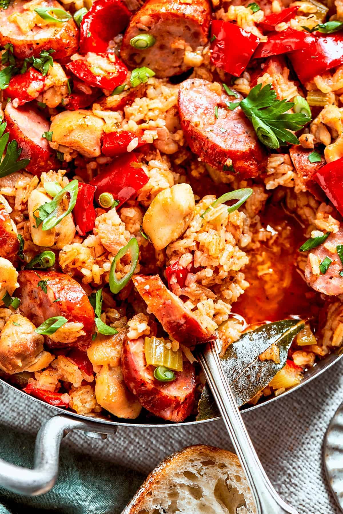 A pan of jambalaya with a serving spoon stirring through it.