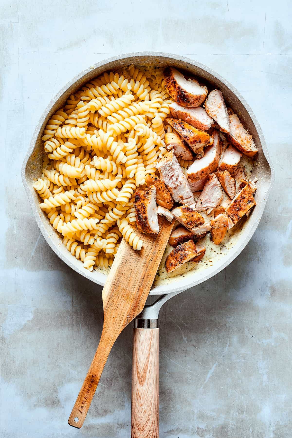 Adding chicken and pasta to the sauce.
