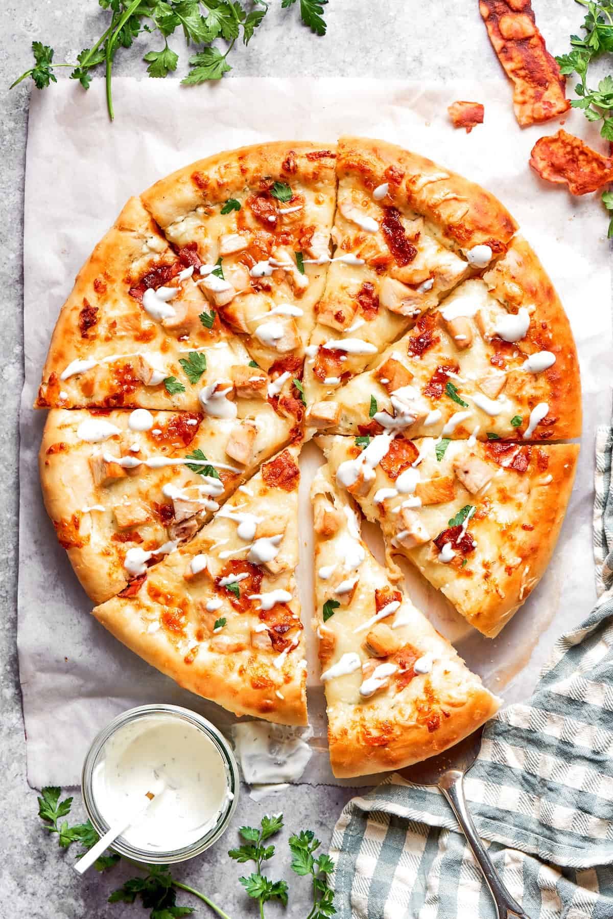 A chicken bacon ranch pizza served with sauce.
