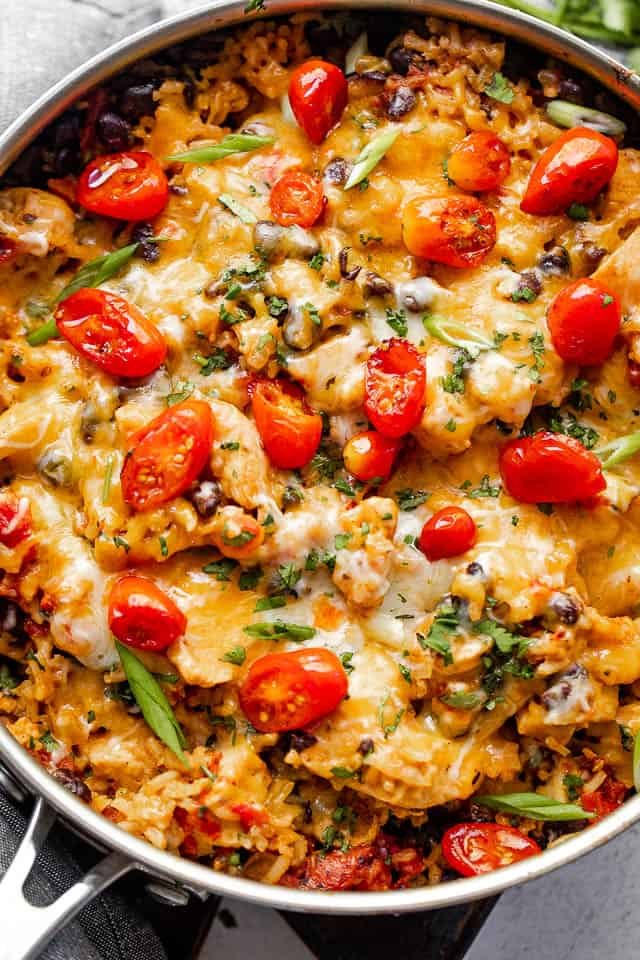 Overhead shot of chicken and rice burrito skillet topped with grape tomatoes.