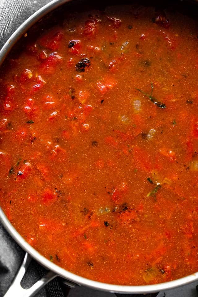Tomato sauce cooking in a stainless steel skillet.