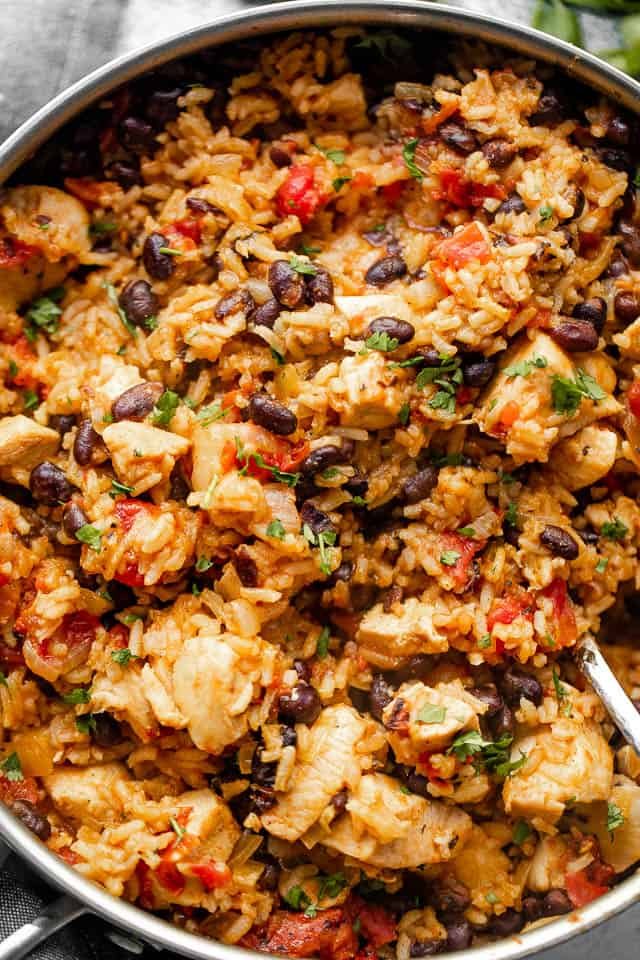 Mixing through rice and chicken in a skillet.