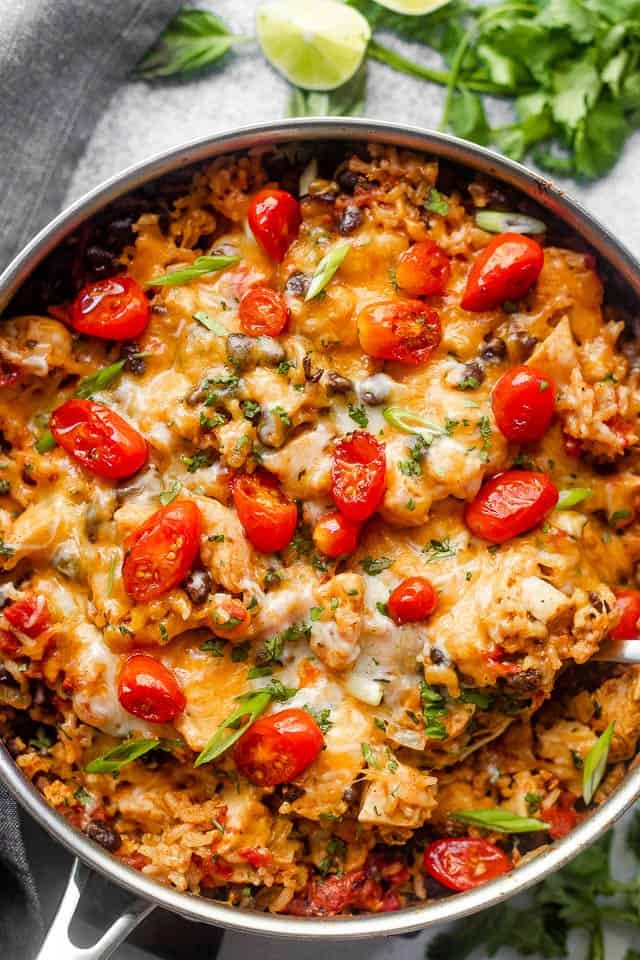 Overhead shot of chicken and rice burrito skillet topped with grape tomatoes.