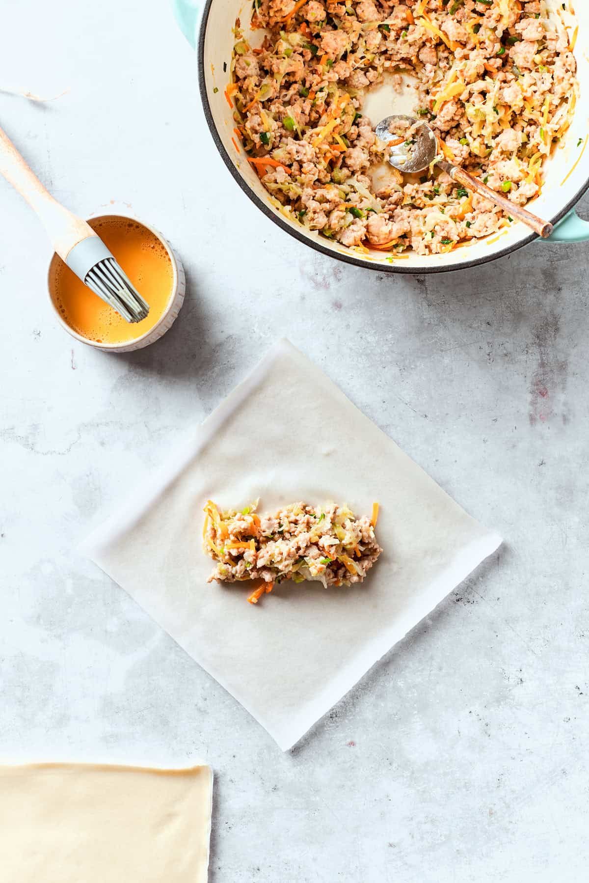 A chicken egg roll is assembled with filling placed in a wrapper.