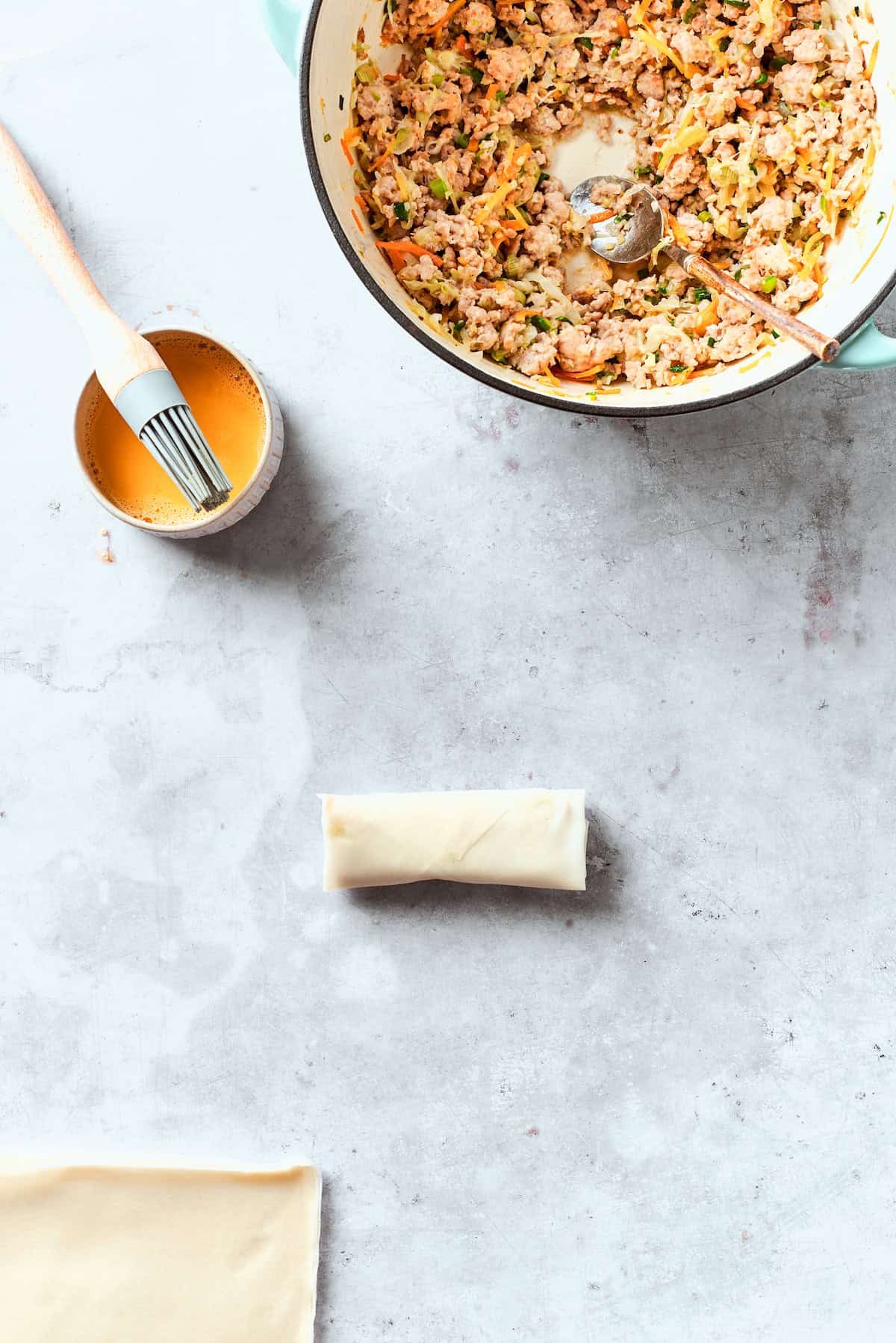 Egg wash is brushed on a chicken egg roll.