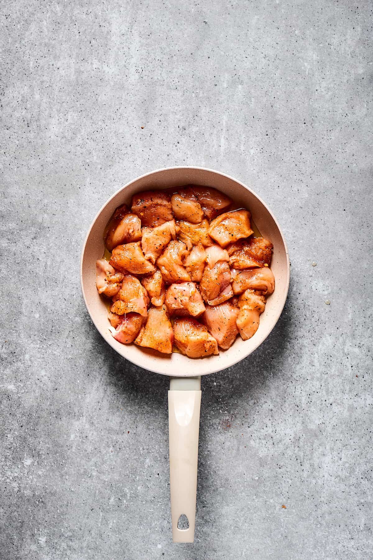 Raw chicken in a skillet.