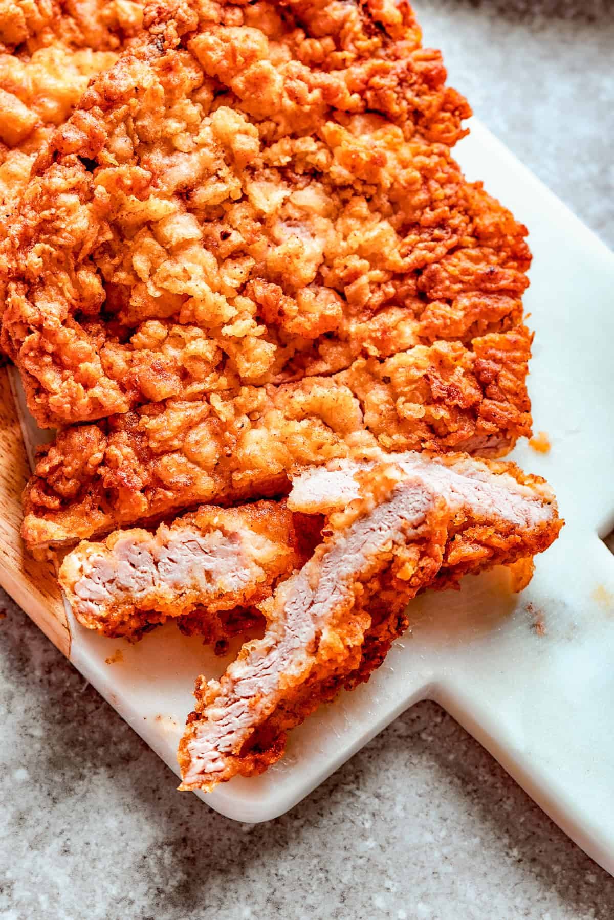 Breaded chicken fried steak on a cutting board.
