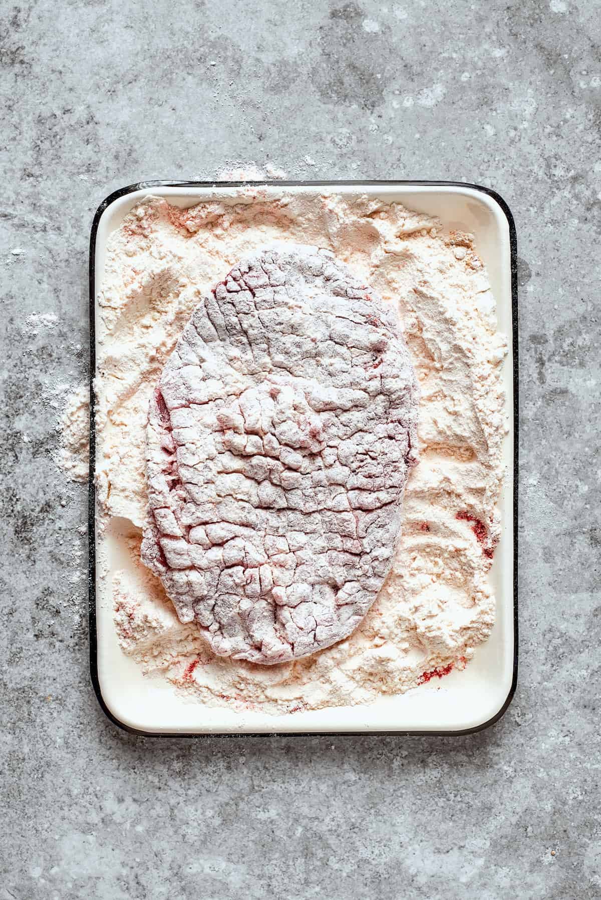 The other side of the steak is coated in flour.