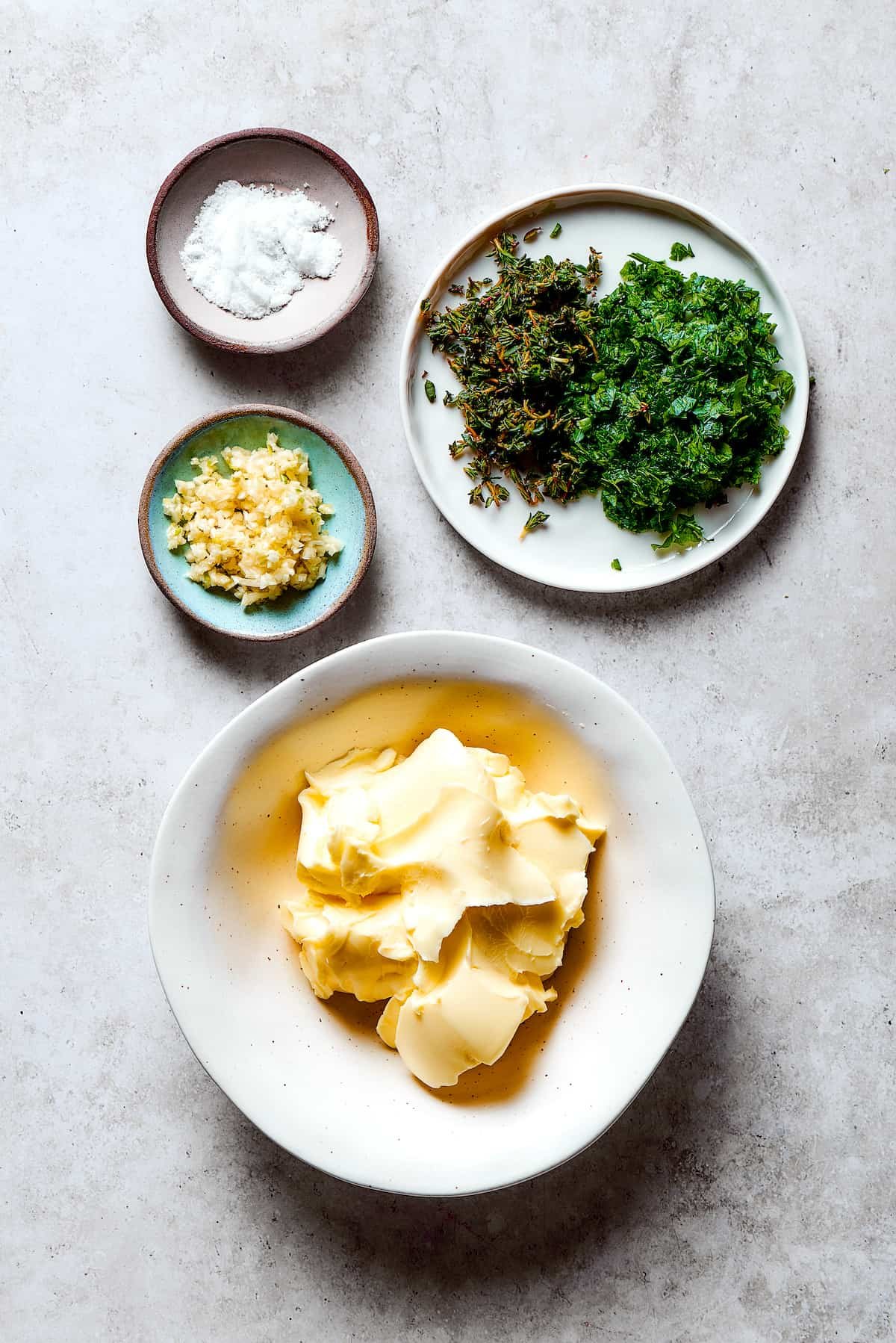 Ingredients for garlic herb butter measured and arranged on a work surface.