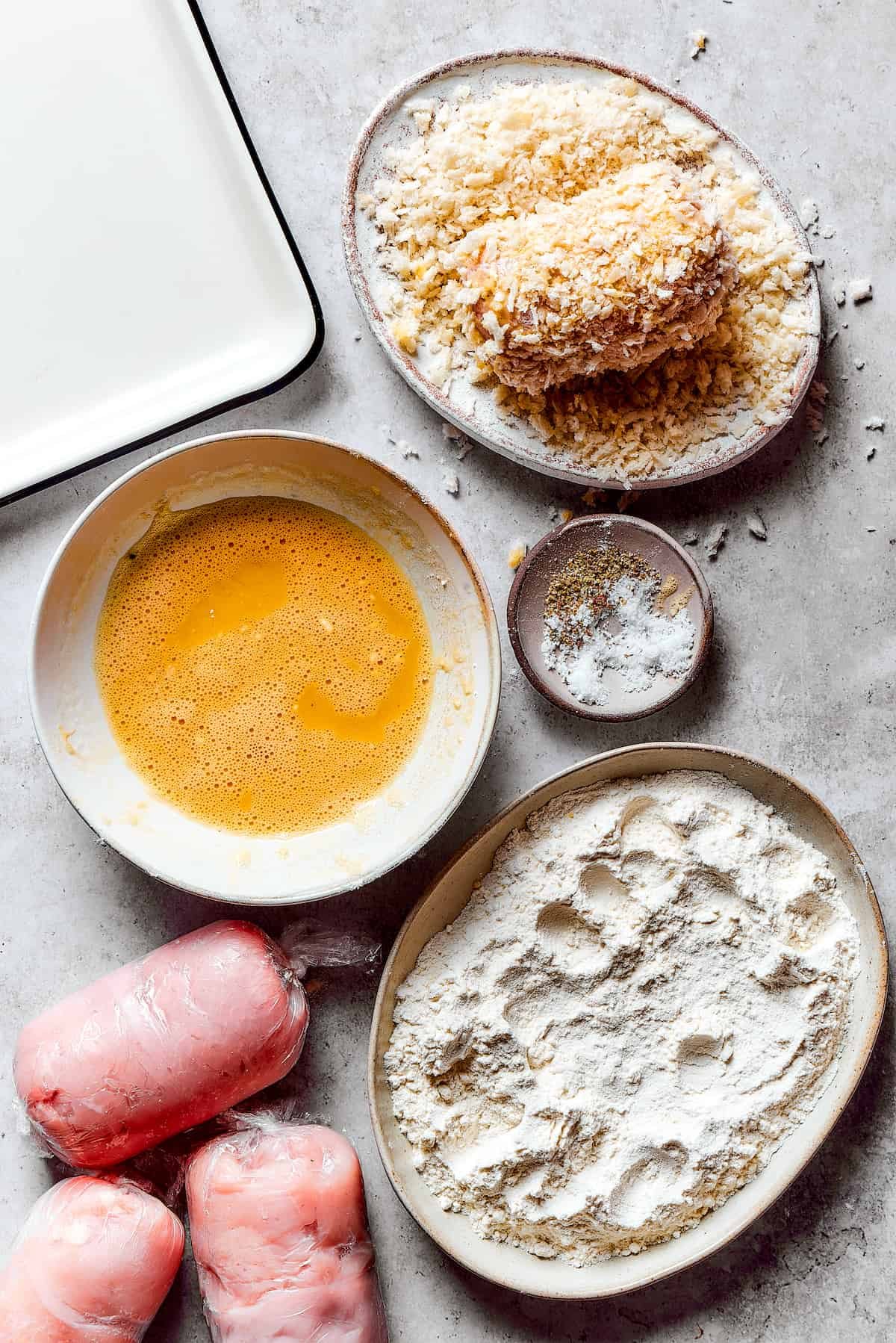 Coating stuffed chicken in breadcrumbs.