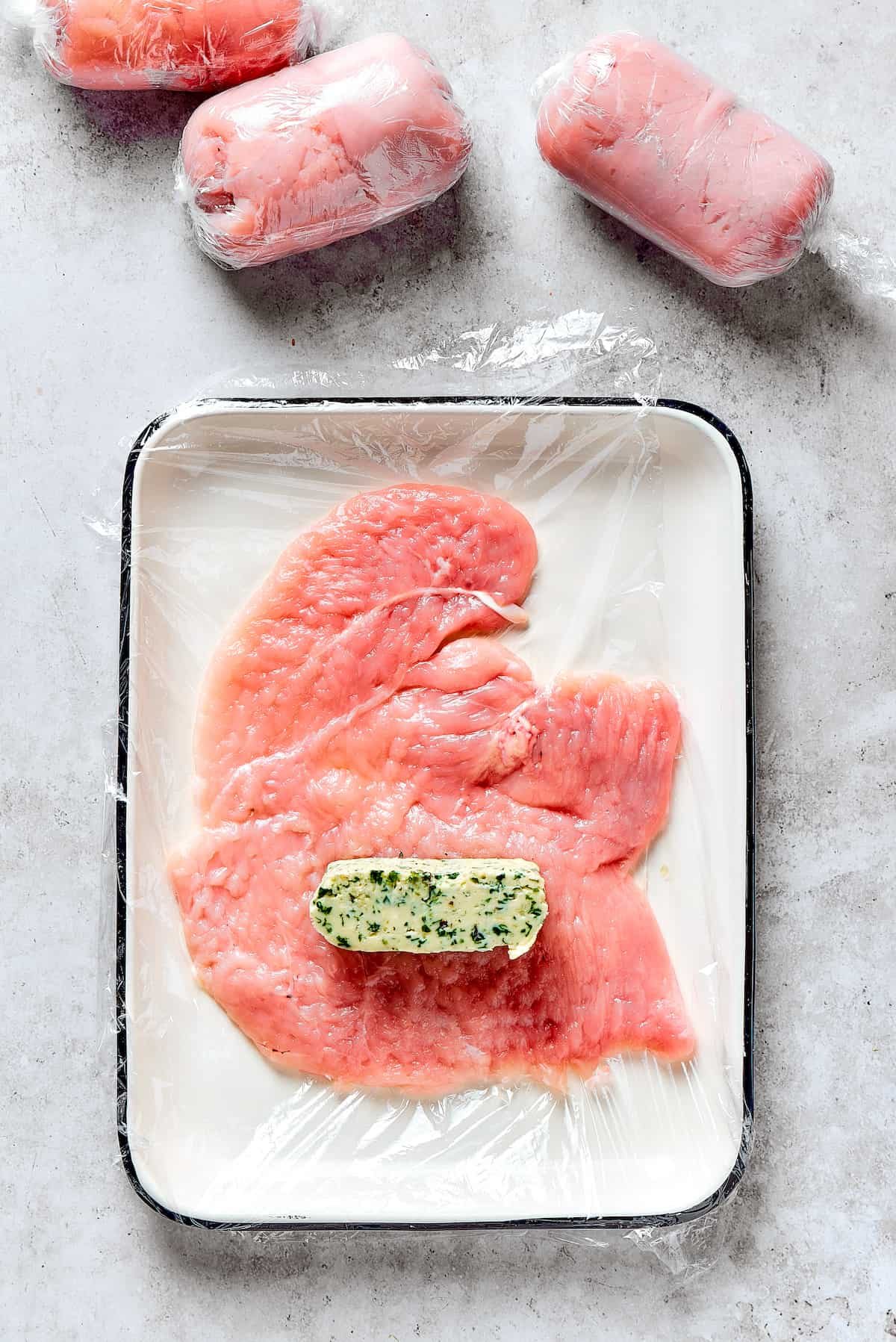 A slice of compound butter on a butterflied chicken breast.
