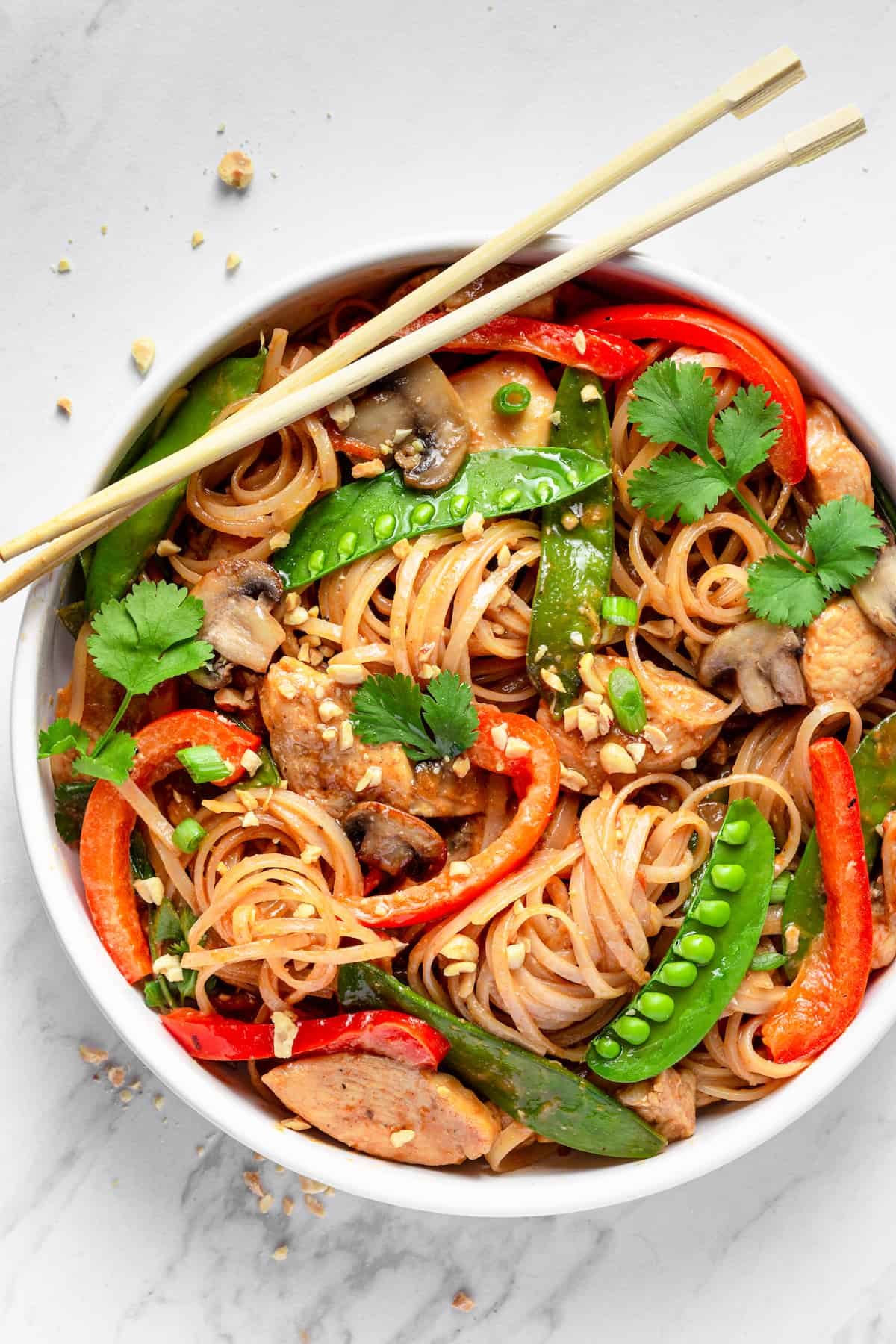 A Bowl of Chicken Lo Mein with a Pair of Chopsticks Resting on the Rim