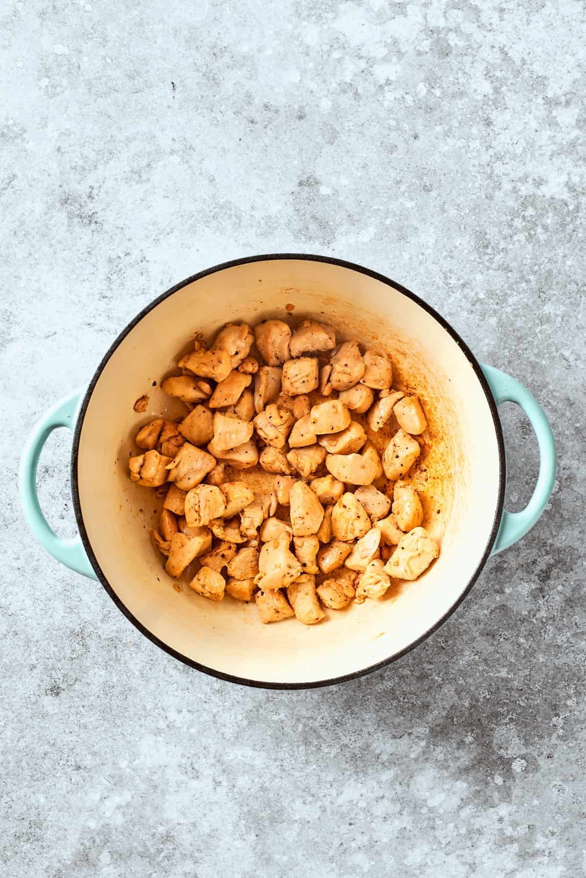 Chicken pieces cook in a pot.