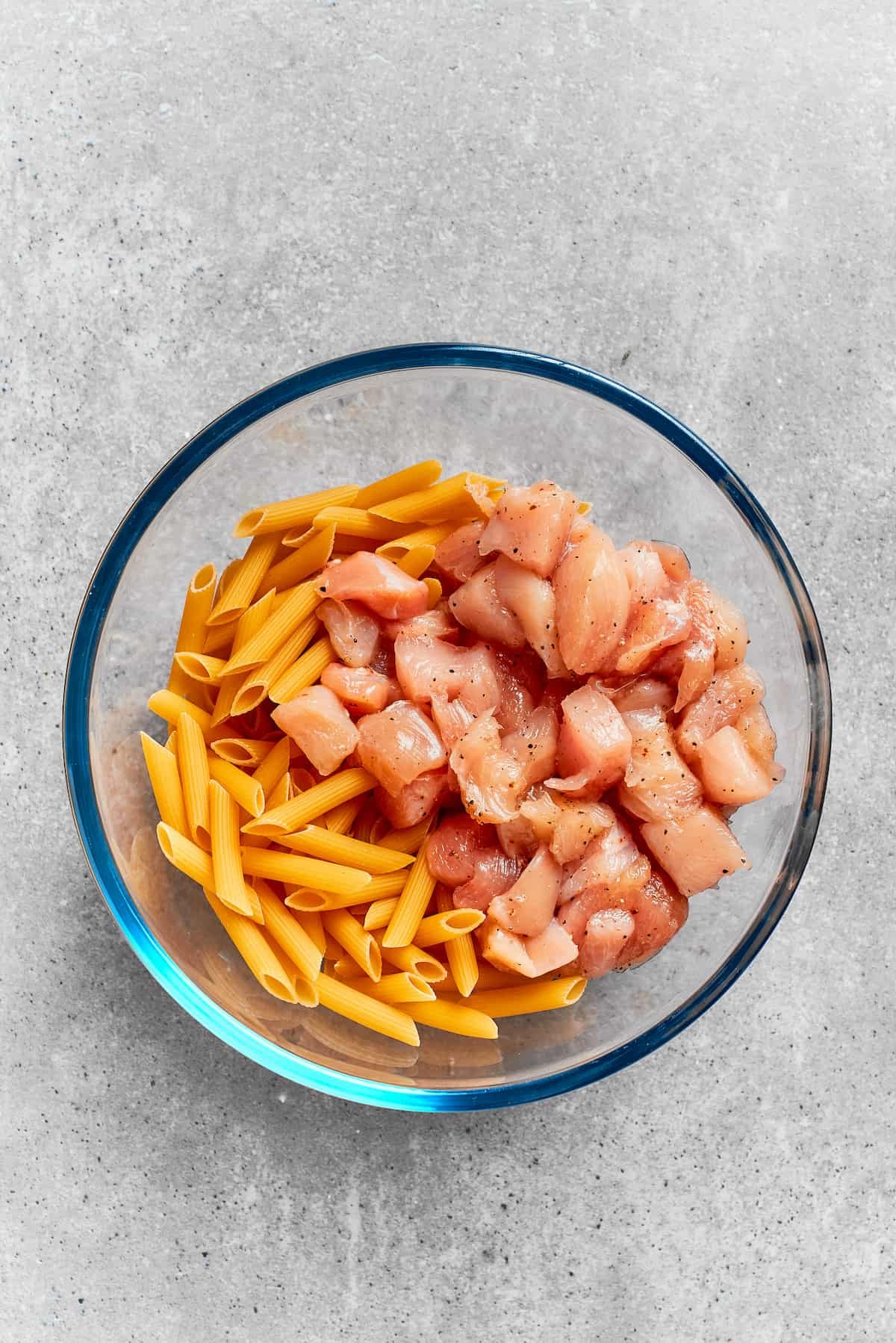 The pasta and chicken are placed in a bowl.