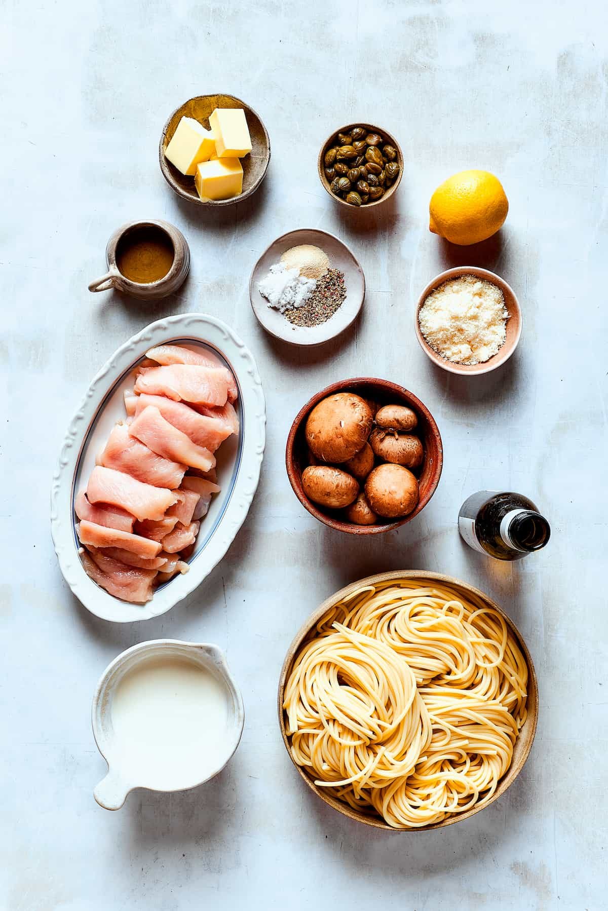 Ingredients for a chicken piccata cheesecake factory copycat, arranged on a work surface.