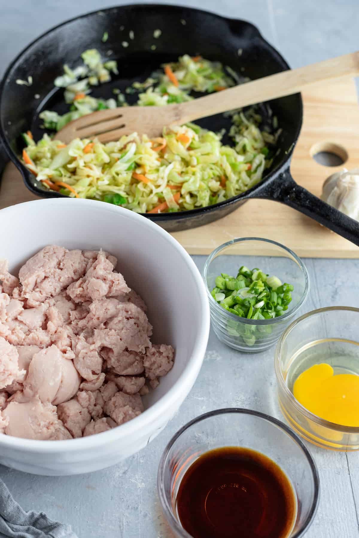 A Bowl of Ground Chicken, a Dish of Soy Sauce and the Rest of the Filling Ingredients on a Table