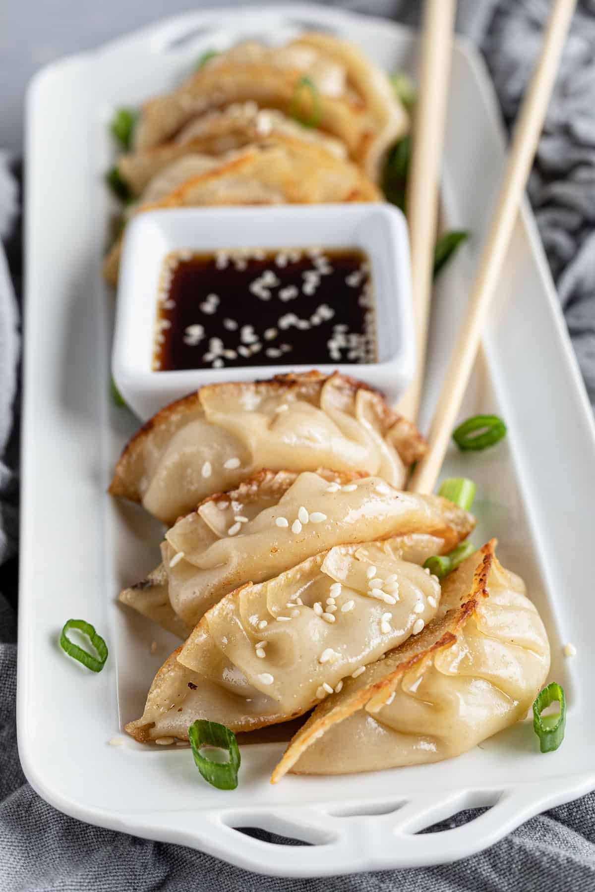 Seven Chicken Dumplings on a Serving Platter with Dipping Sauce and a Pair of Chopsticks