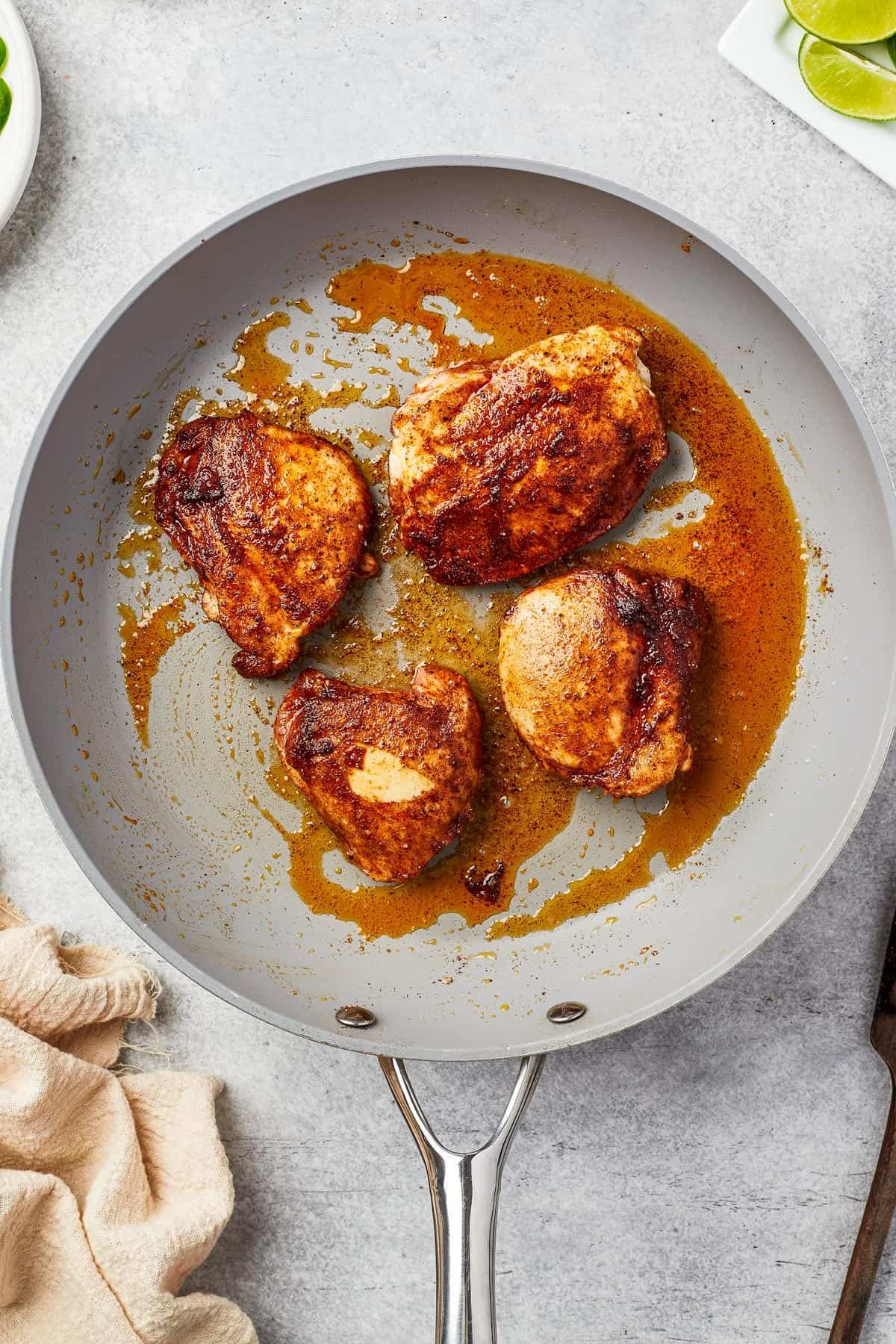 Chicken thighs cooking in a skillet.