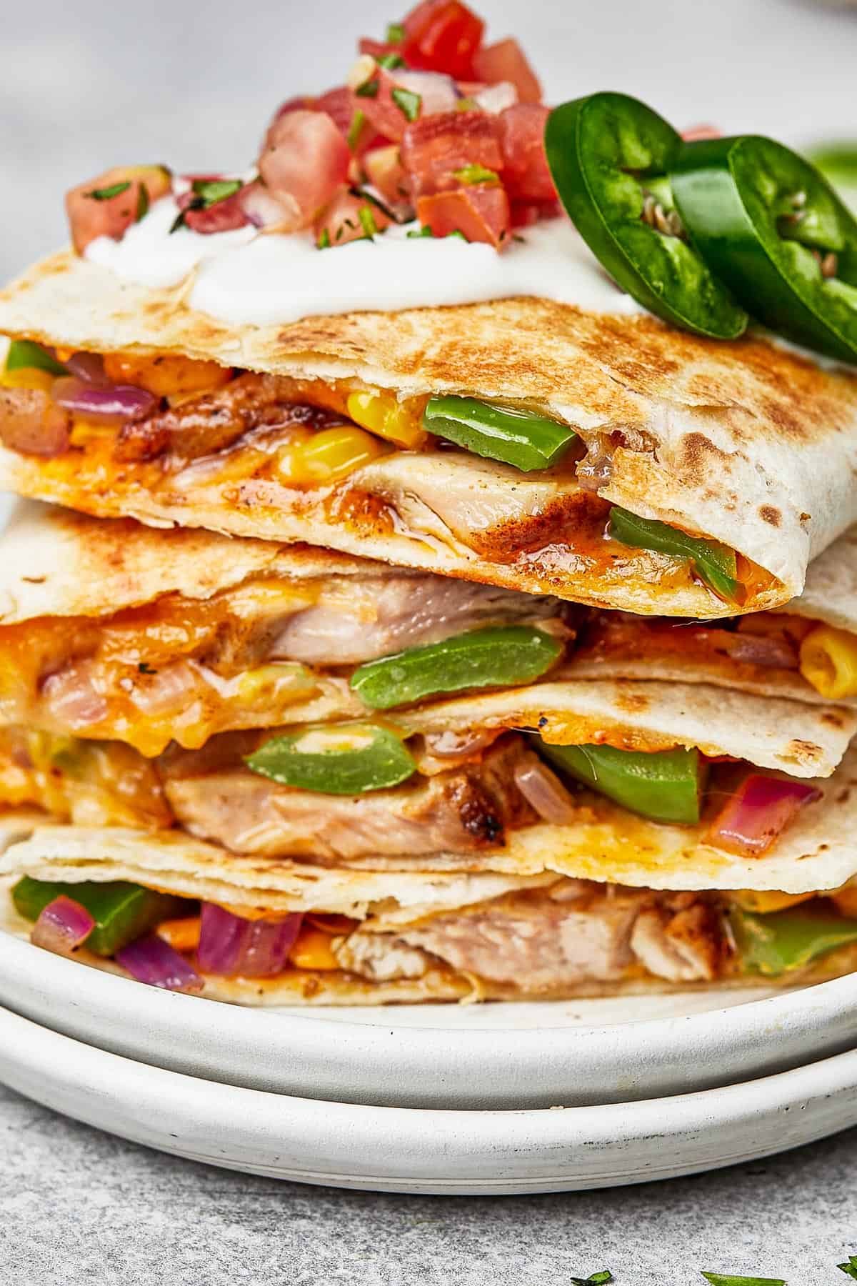 Chicken quesadillas stacked on a plate, viewed from the side to show texture.