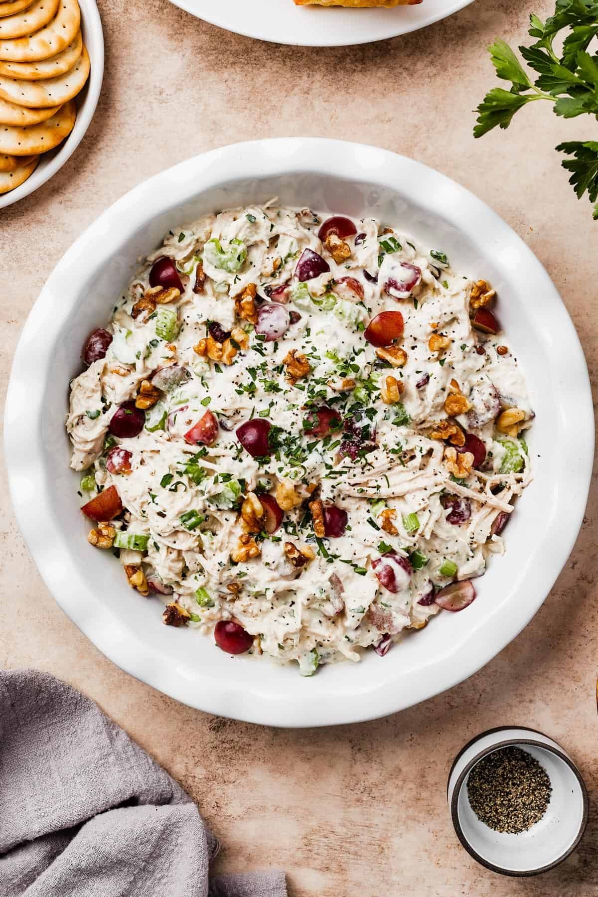 A shallow white dish filled with creamy chicken salad, garnished with nuts.