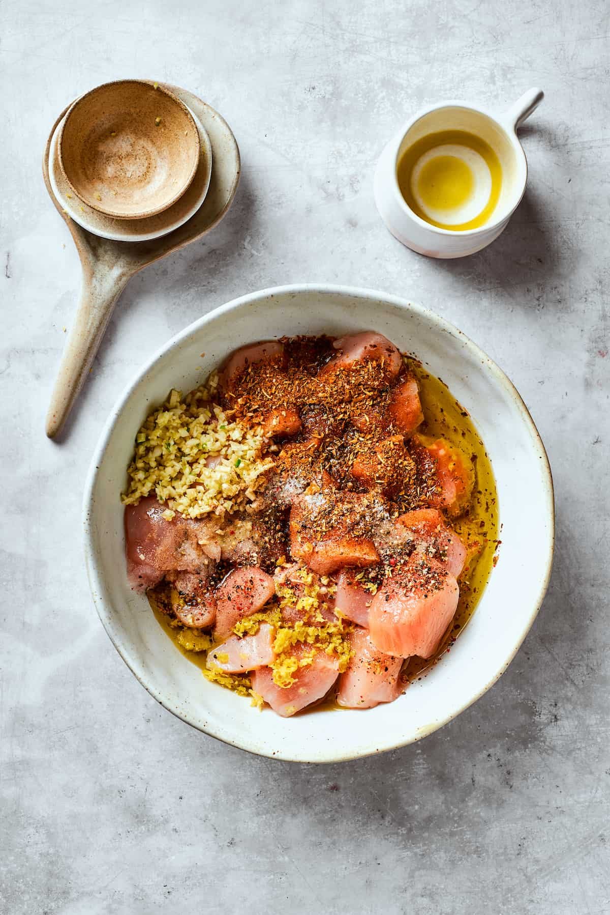 Lemon zest is added to chicken in a bowl for chicken souvlaki.