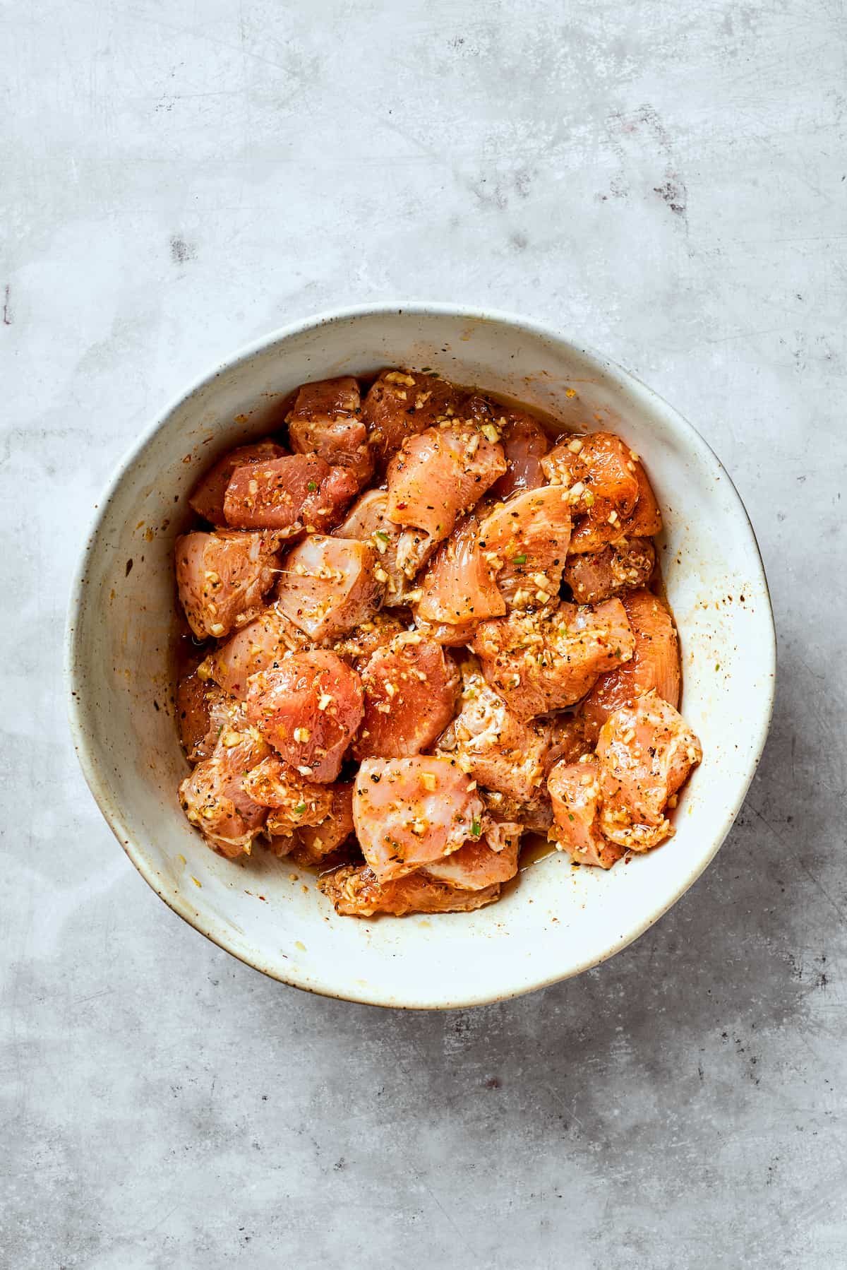 Chicken marinates in a bowl for chicken souvlaki.