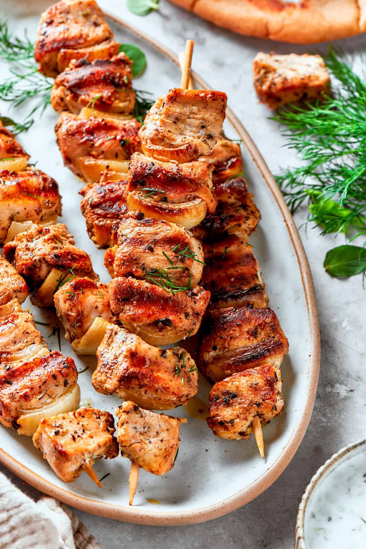 A platter of several skewers of chicken souvlaki.