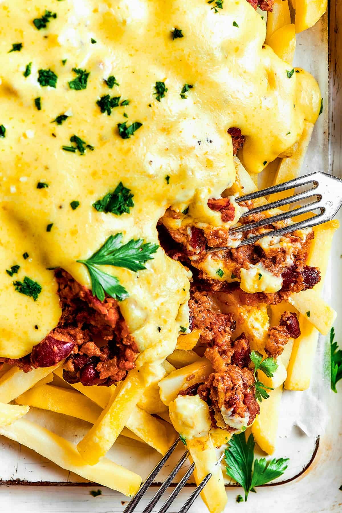 A fork taking a bite from a batch of chili cheese fries.