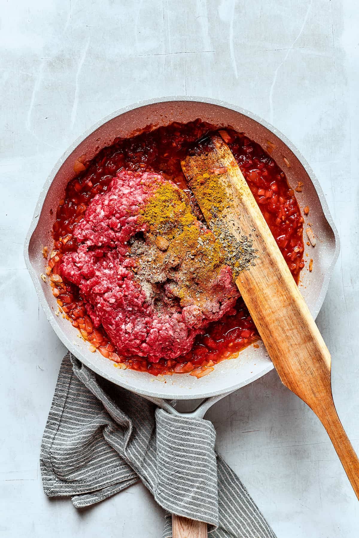Adding beef and other ingredients to a skillet.