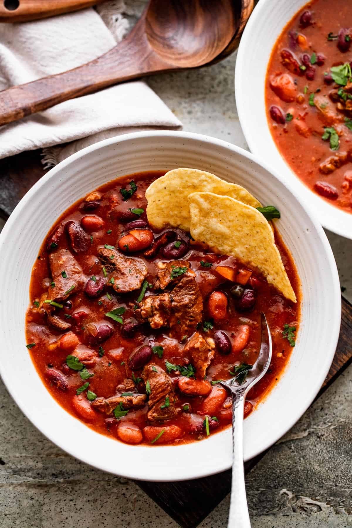 Chili con Carne served in two white bowls, and a couple of tortilla chips set inside the bowls.
