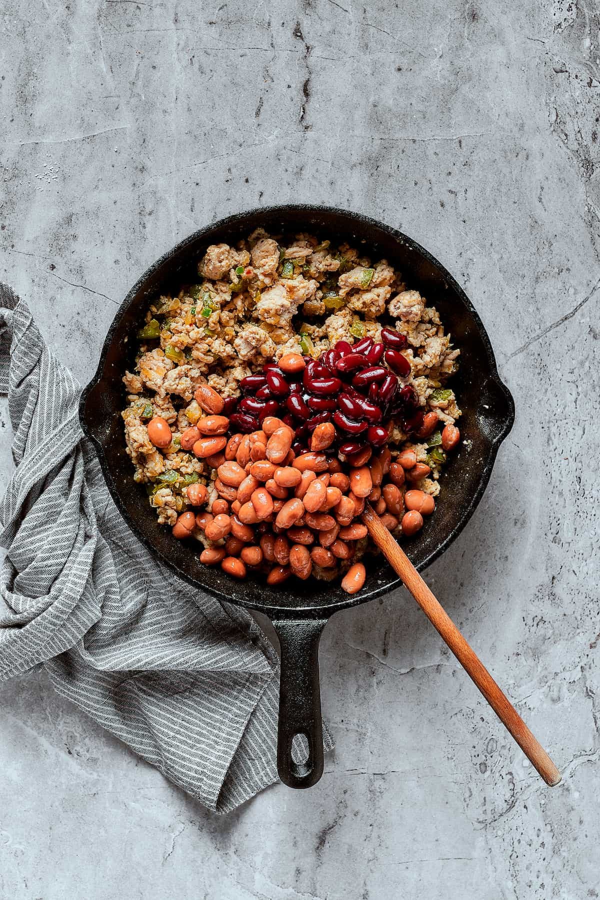 Adding beans to a skillet.