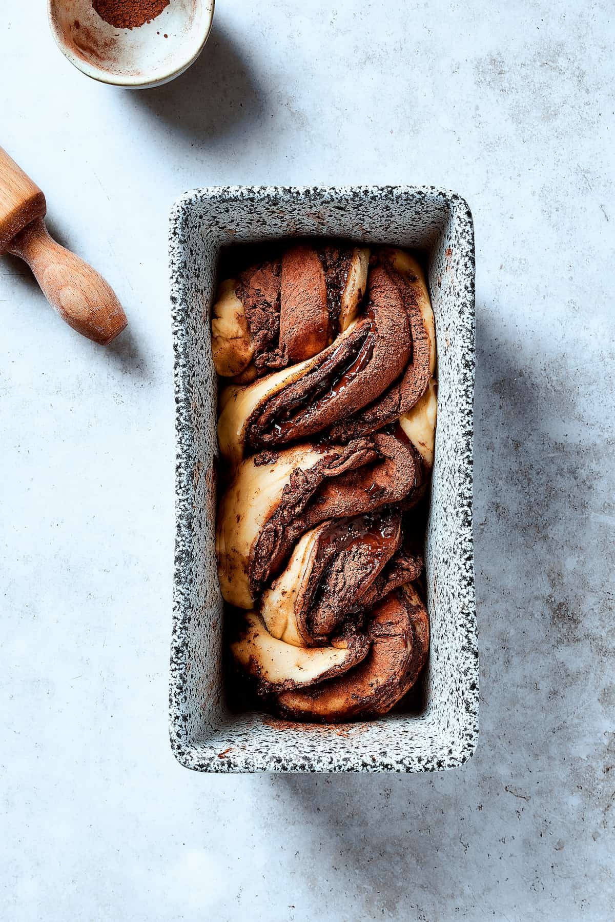 Twisted lengths of chocolate-filled dough placed in a loaf pan.