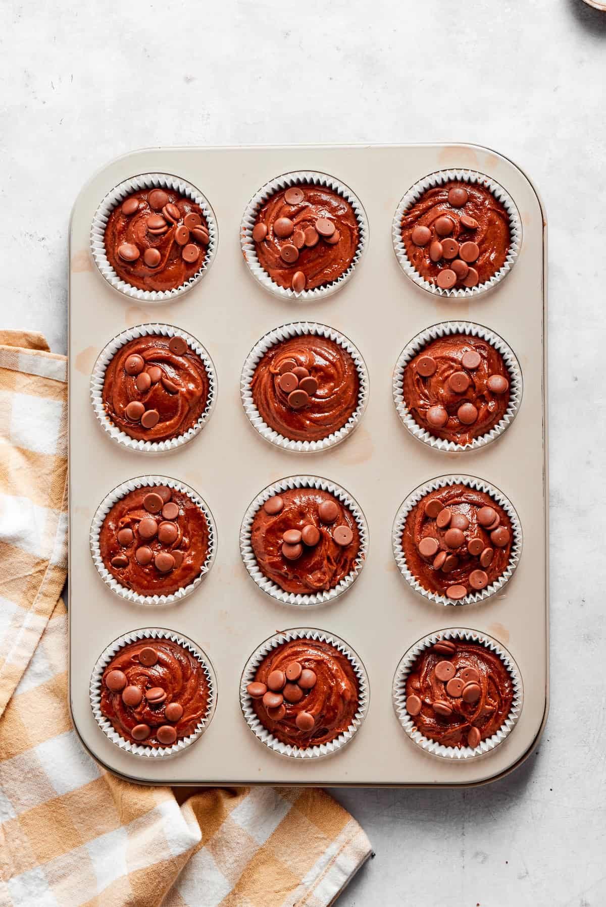 Chocolate muffin batter is divided into a muffin tin.