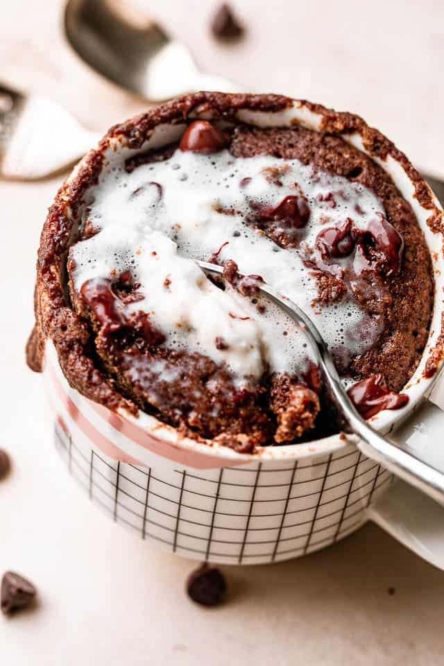spooning out mug cake topped with whipped cream