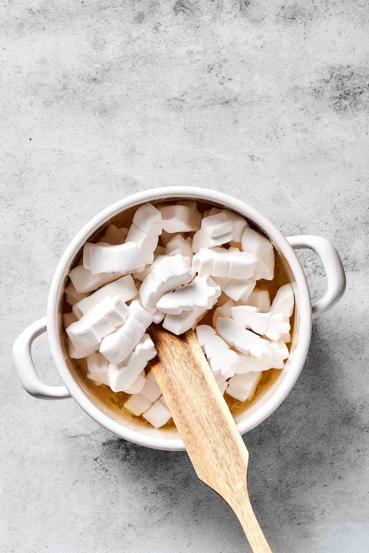 Stirring marshmallows into melted butter.