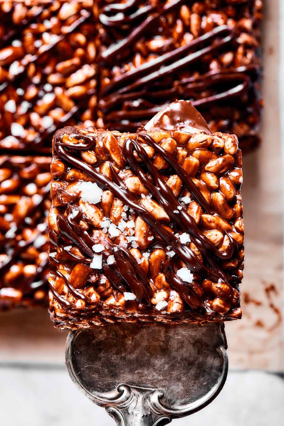 Lifting a chocolate cereal bar square with a silver dessert server.
