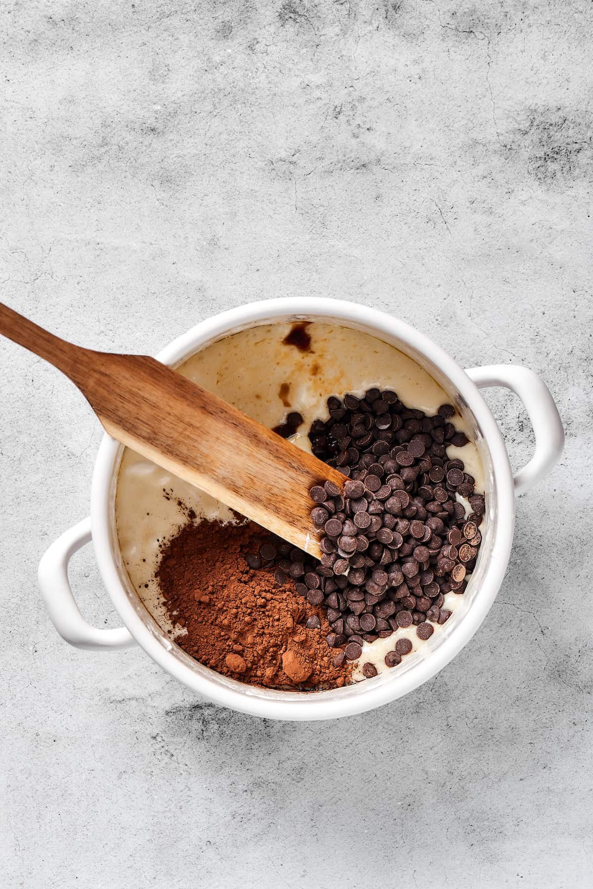 Stirring chocolate chips and cocoa powder into a melted butter mixture.