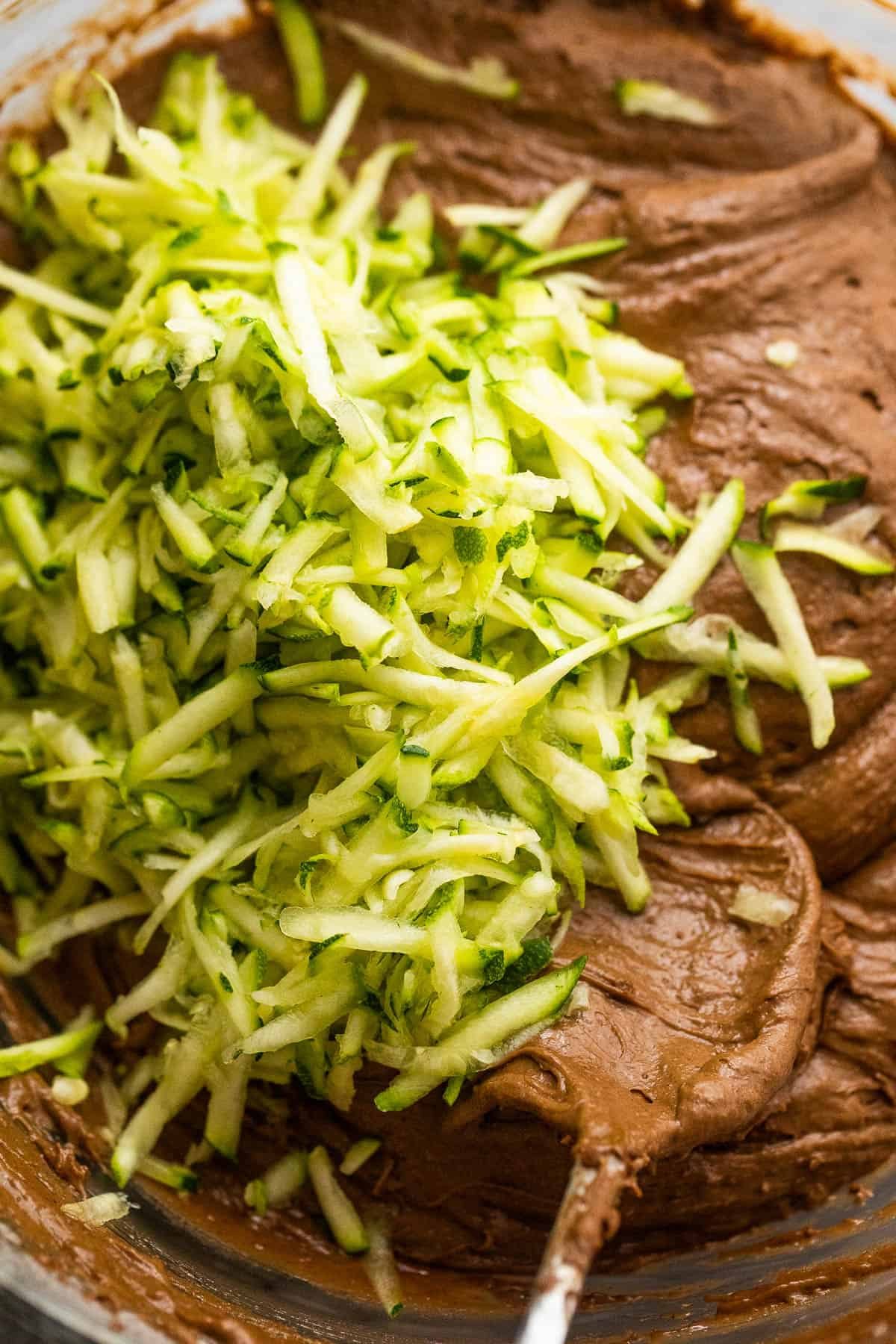 mixing shredded zucchini into a chocolate batter for zucchini bread