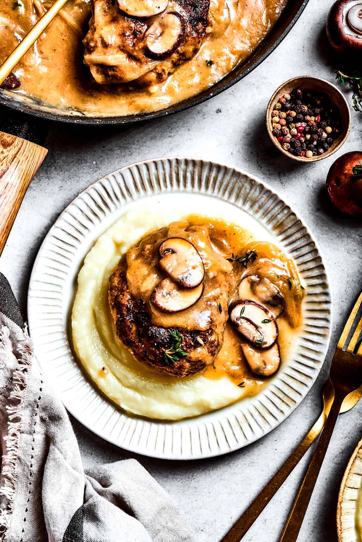 A serving of chopped steak on top of mashed potatoes.