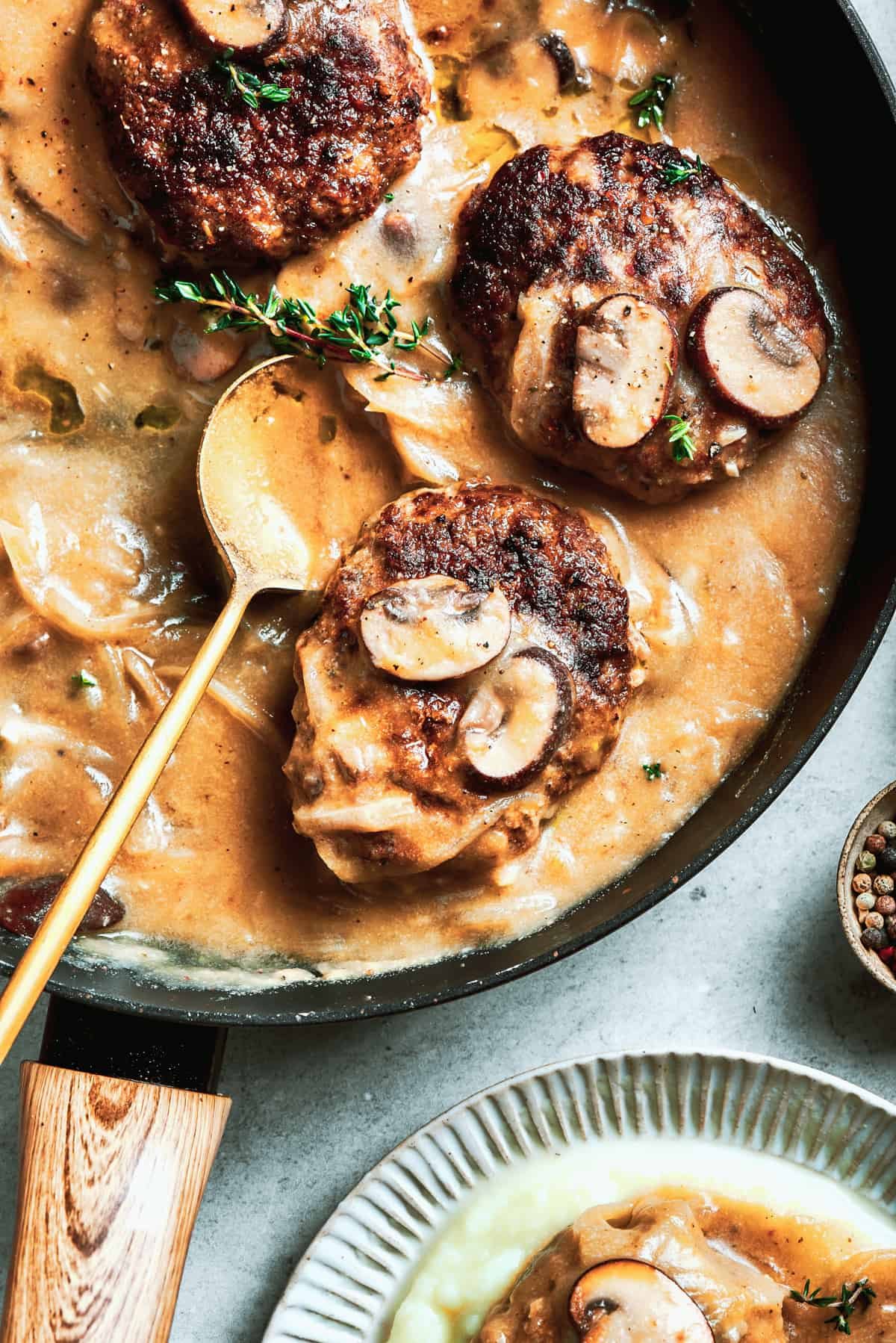 A pan of steak and gravy with a serving spoon resting in it.