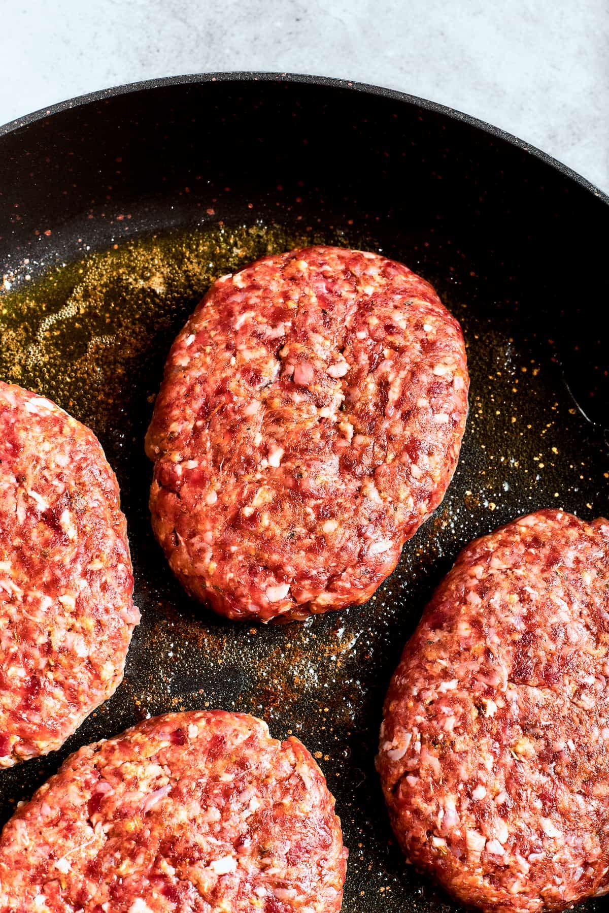 Beef patties brown in a skillet for chopped steak.