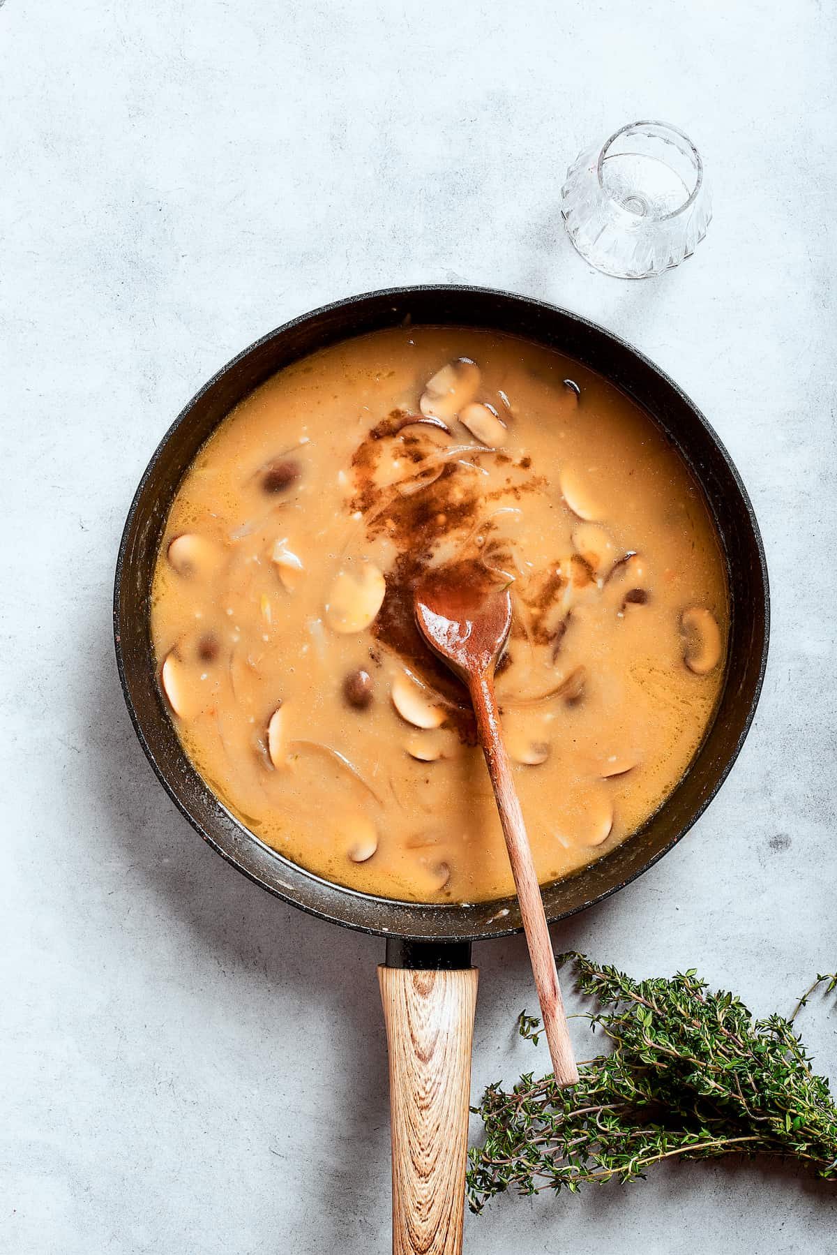 A wooden spoon stirs the gravy.