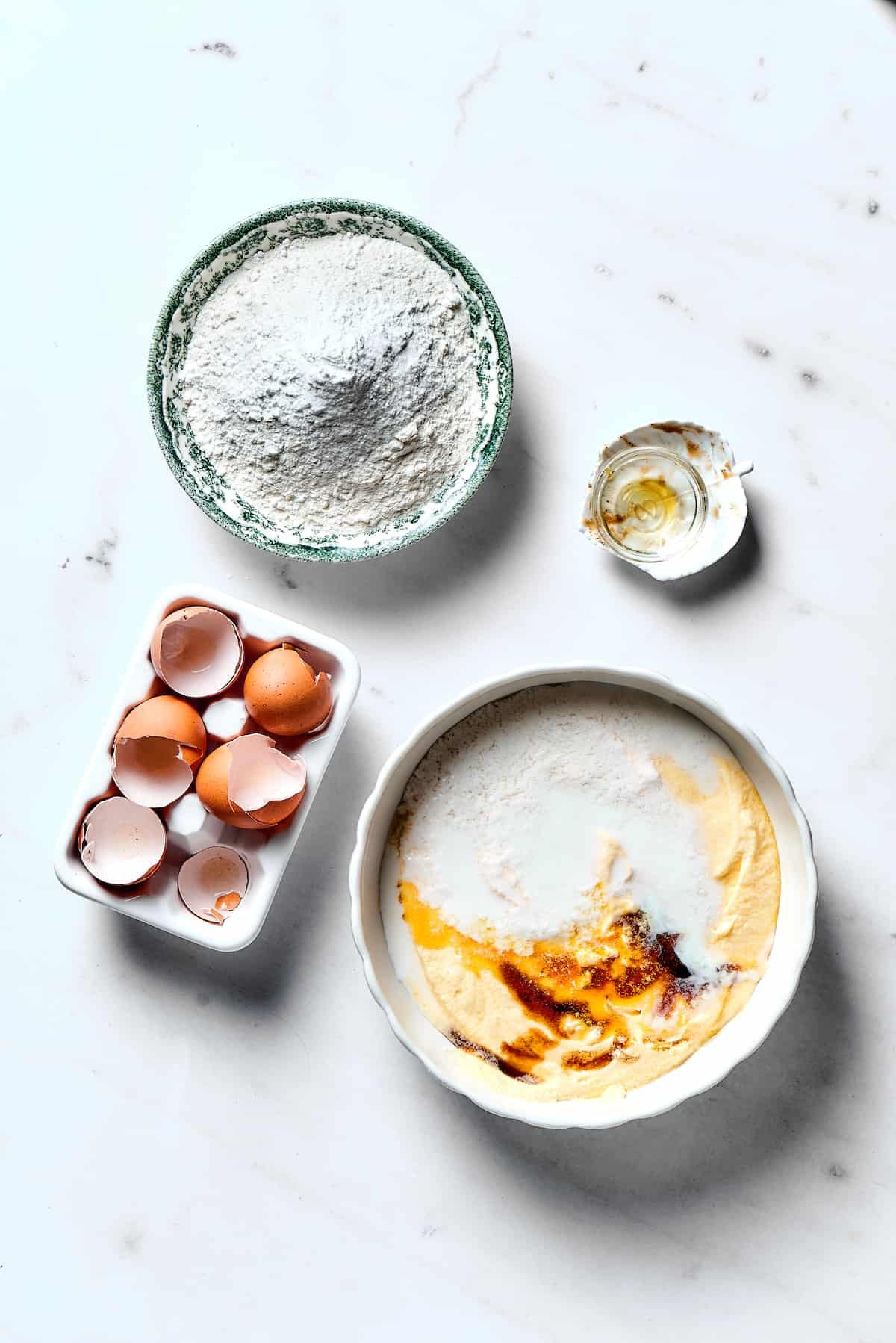 Wet ingredients being mixed, while dry ingredients are in a bowl nearby on the table.