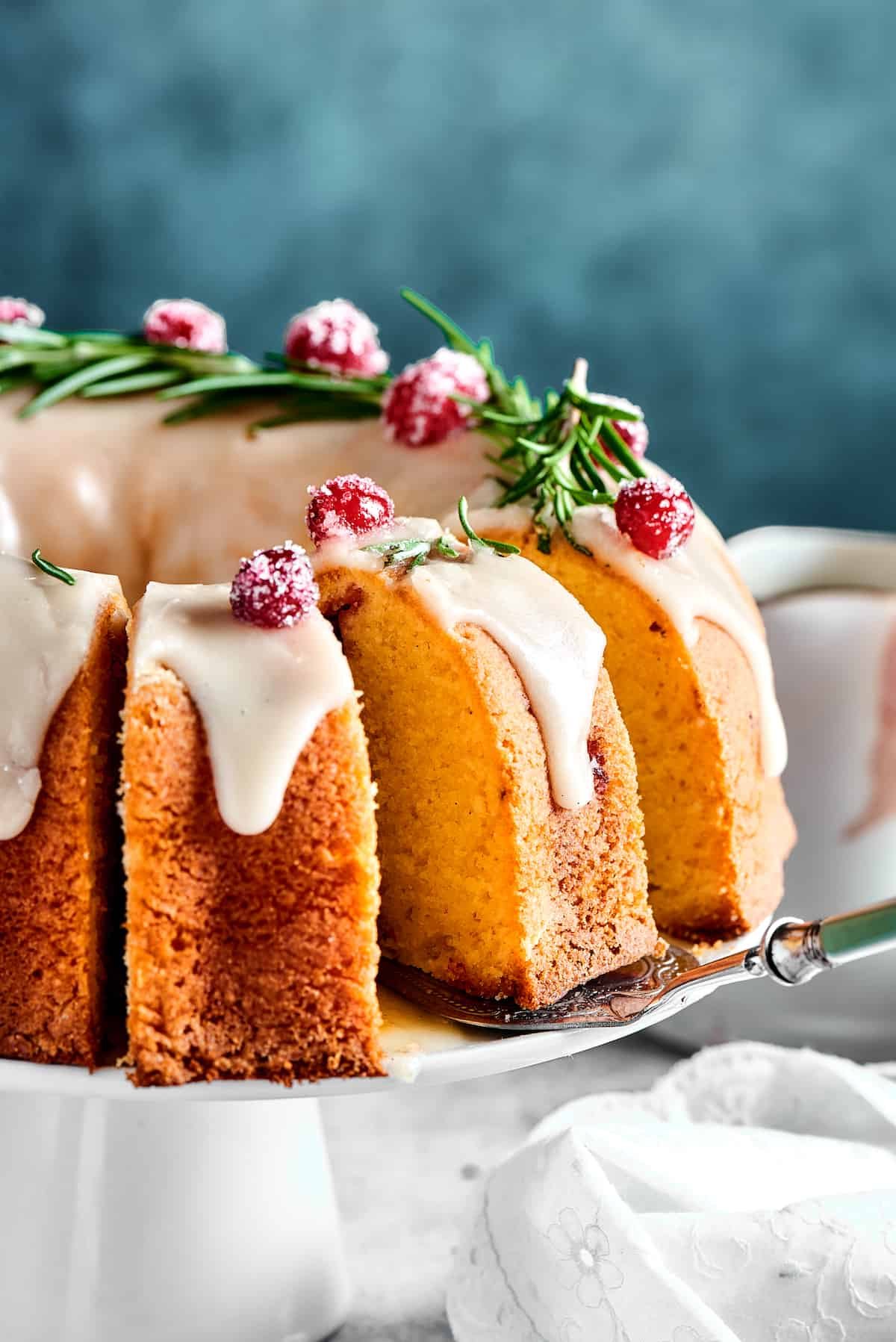 A cranberry cake on a cake stand. Part of the cake has been sliced.