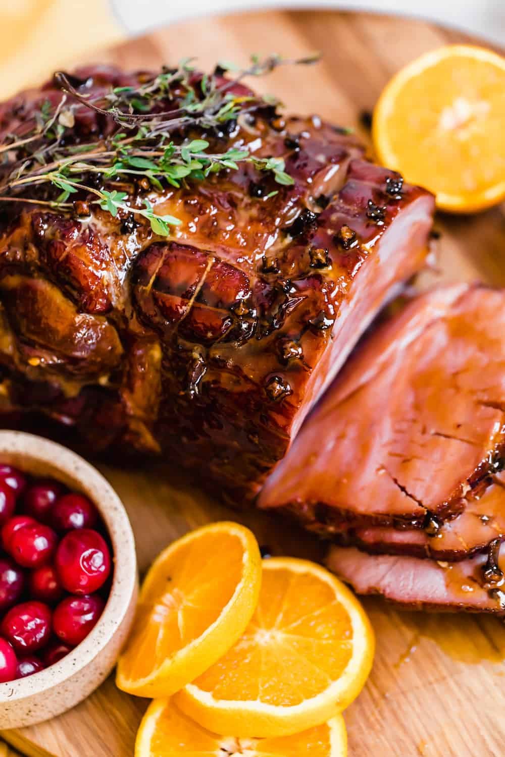 Slices of Christmas Ham on a Circular Wooden Surface with Assorted Fruits