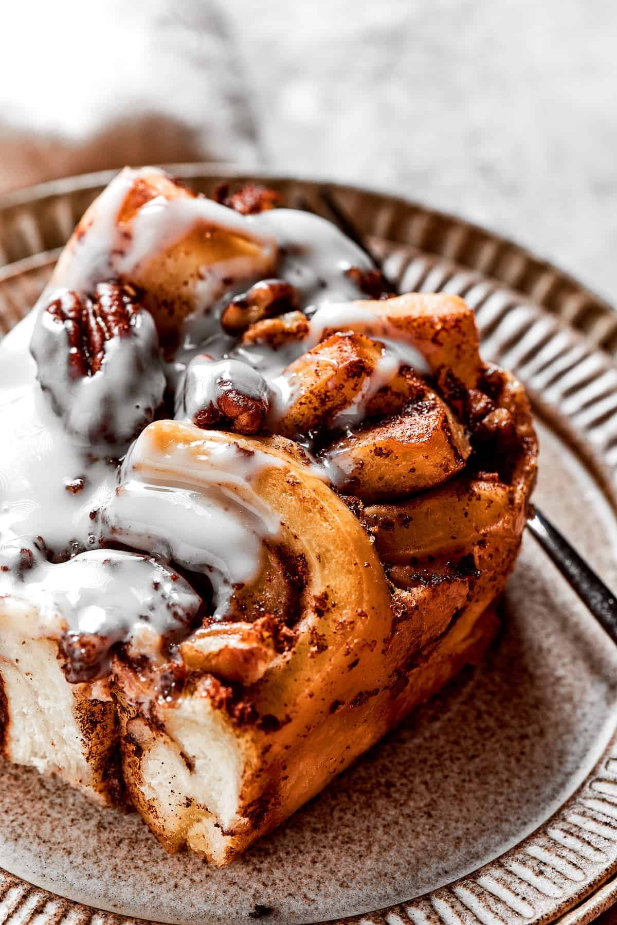 Close up of a square of cinnamon roll casserole on a plate with a fork