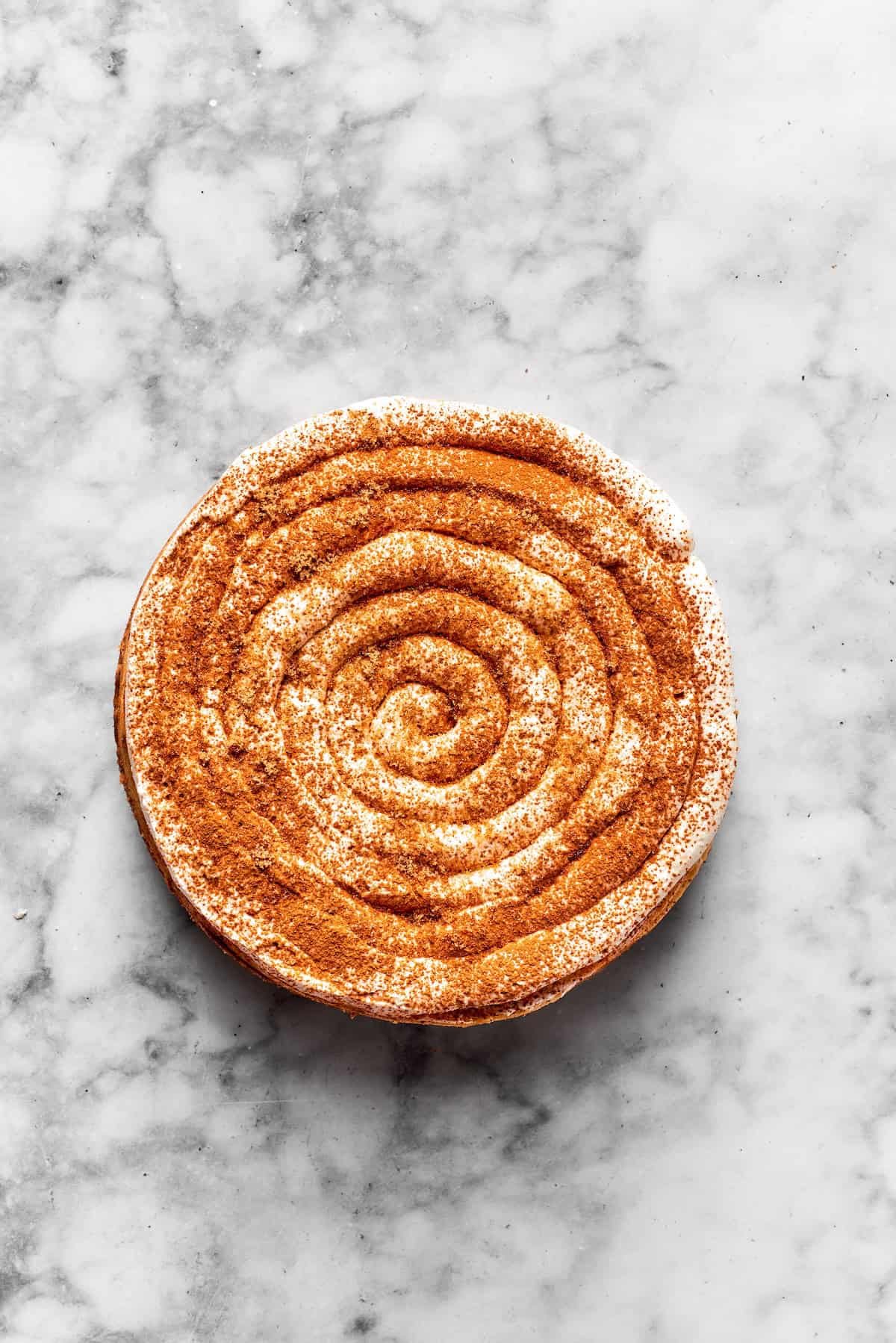 Frosting is piped onto a cinnamon roll cheesecake.